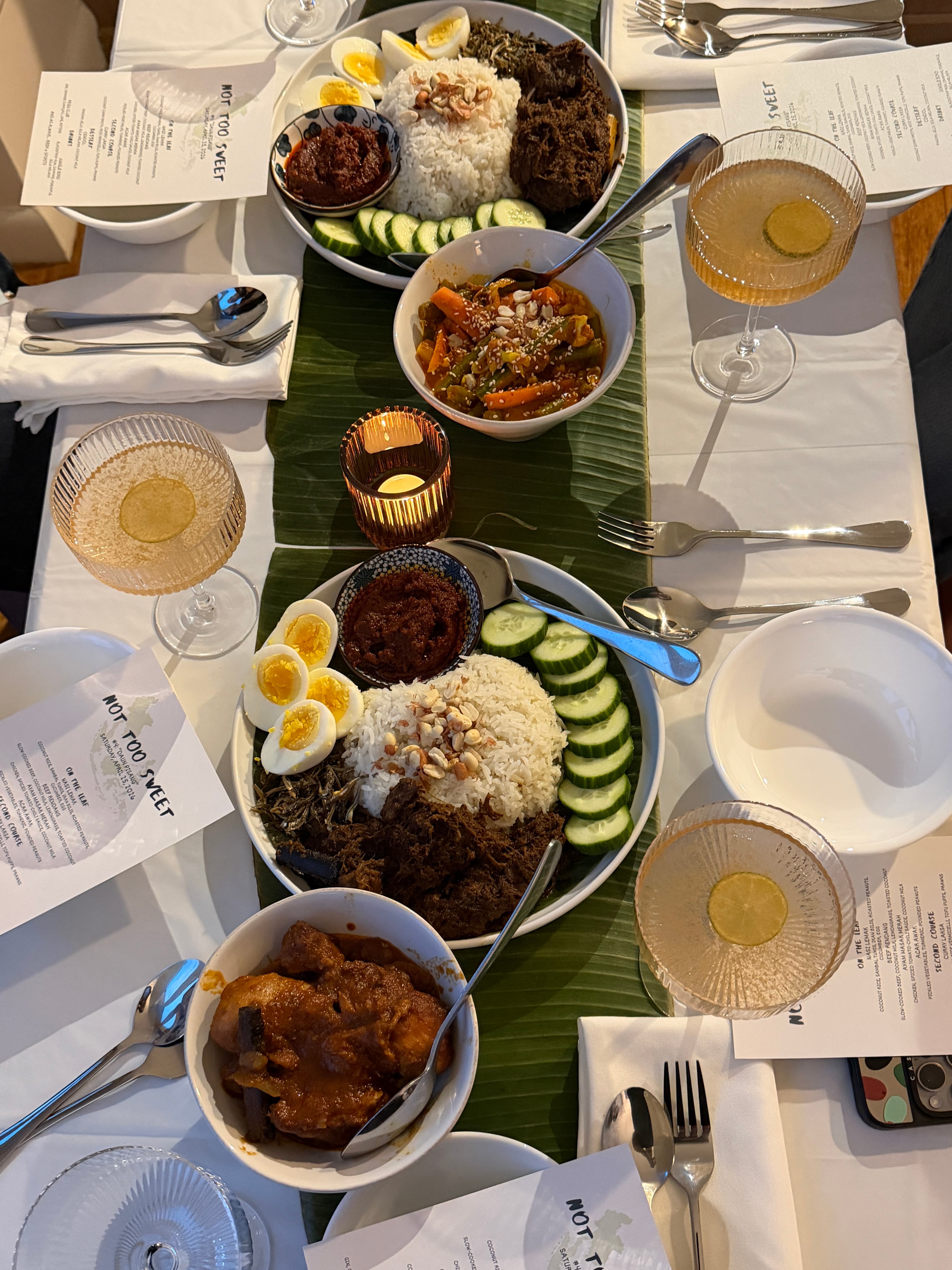 Nasi lemak on a banana leaf: coconut rice, sambal, ikan bilis, egg, cucumber, and peanuts