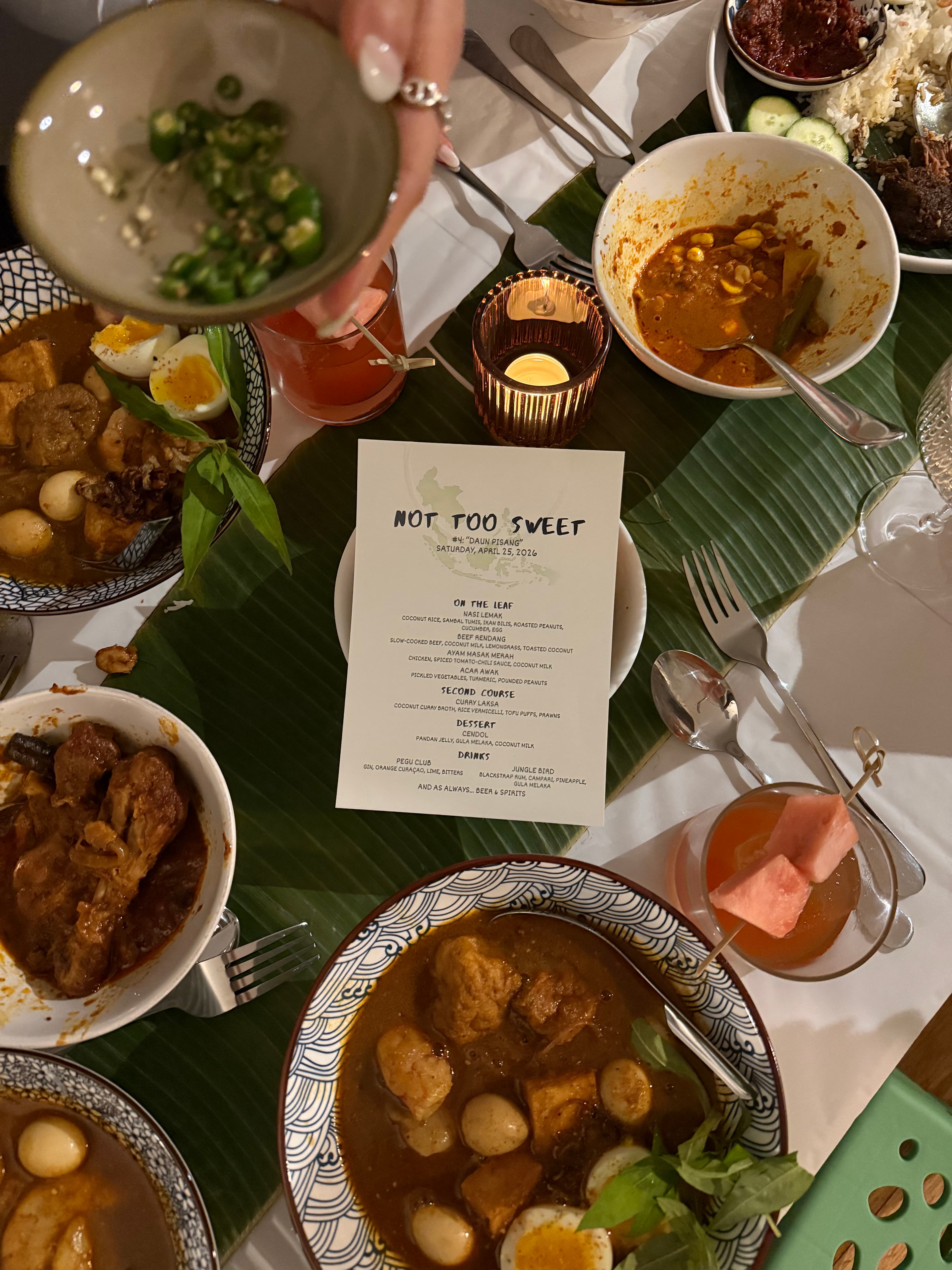 The Daun Pisang table, bowls of curry on banana leaf around the printed menu